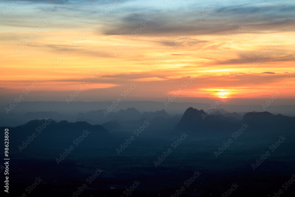 Sunset landscape orange sky and silhouette mountain with fog at