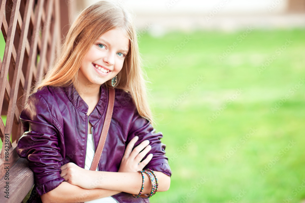 Fototapeta premium Happy teenage girl 12-15 year old posing outdoors over green nature background. Looking at camera. Childhood.