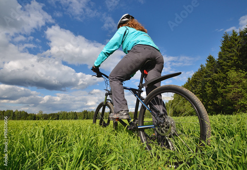woman riding a mountain bike on a background of the blue sky