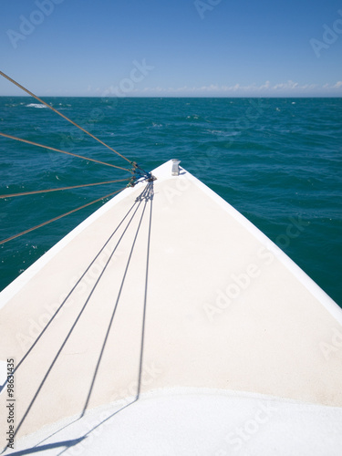 bow of a yacht boat with a green sea and blue sky backdrop