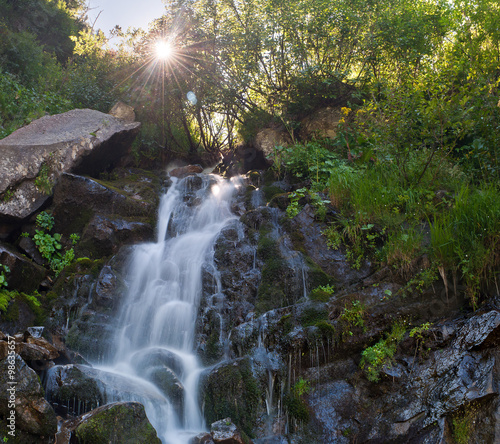 Summer landscape with sun and a waterfall in the Carpathians