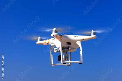 White drone with hovering with blue sky in the background photo