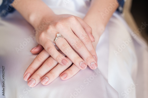 Bride hand with manicure on wedding dress