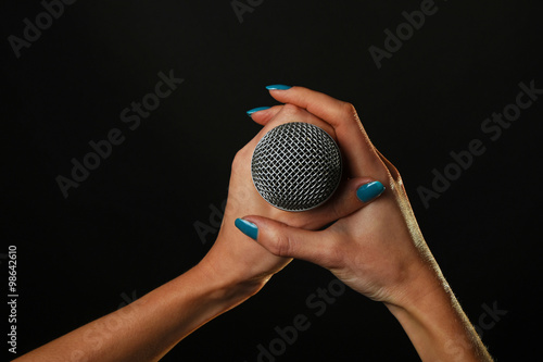 Konstfotografi Woman hands with microphone isolated on black
