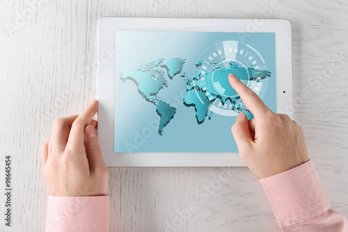 Close up of human hand touching screen of tablet pc with world map and network