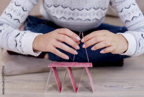 Womans hand building a house out of cards