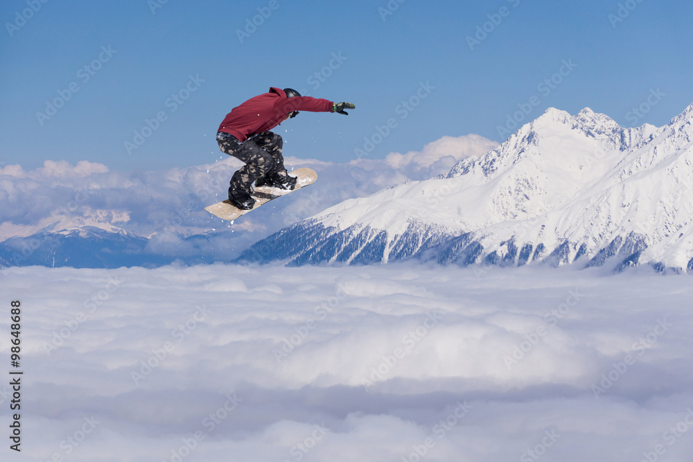 Flying snowboarder on mountains. Extreme sport.