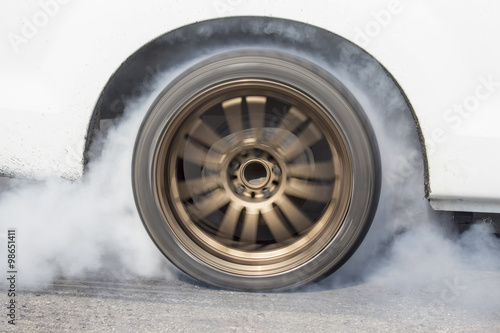 race car burns rubber off its tires in preparation for the race
