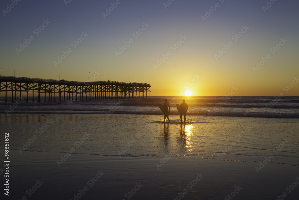 Fototapeta premium surfers at sunset