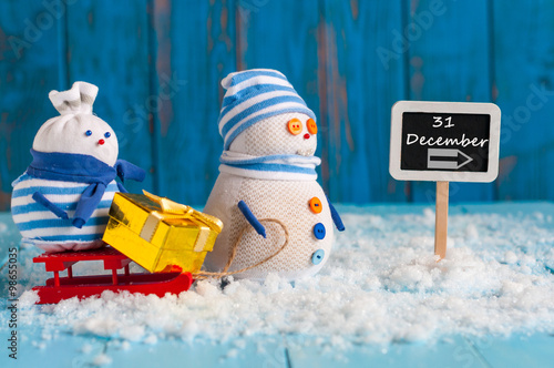 December 31 calendar day written on roadsign. Two snowman with gift, New Year concept photo