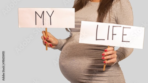 Pregnant woman flipping between Pro Life and My Life signs photo
