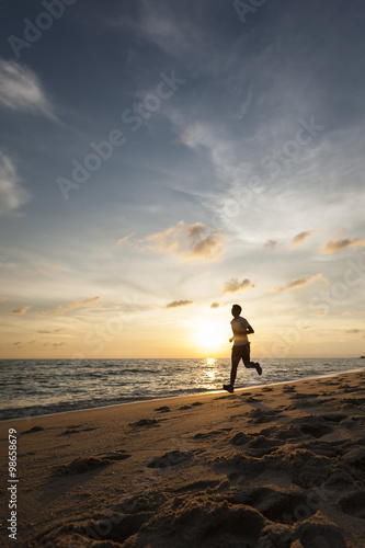 Man running on the beach at sunrise