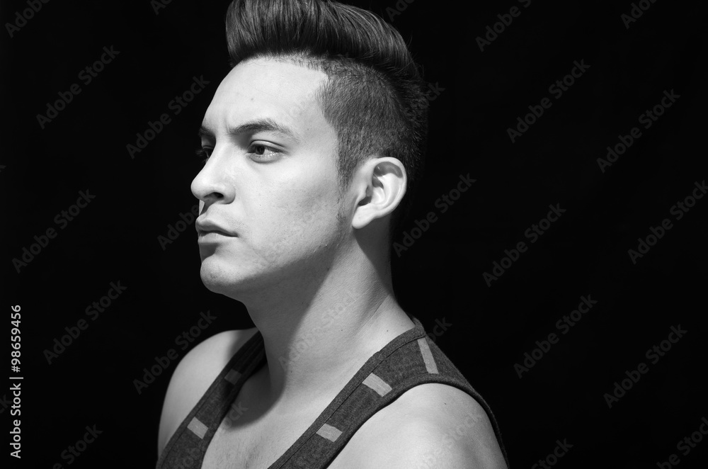 Hispanic male wearing striped singlet, headshot profile artistic with black background