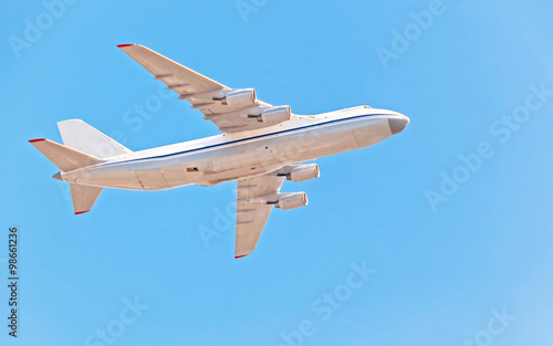 Fotografie An-124-100 Ruslan (Condor) the world largest cargo strategic airlift jet airplane flies against blue sky background