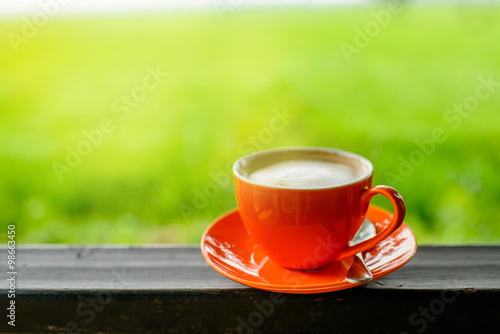 orange coffee cup with nature bokeh background.