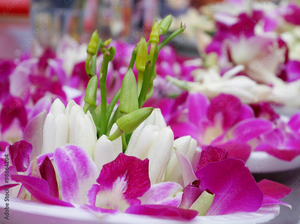 The close up of orchid and white champaka flower offering set on plate at the Chinese temple.