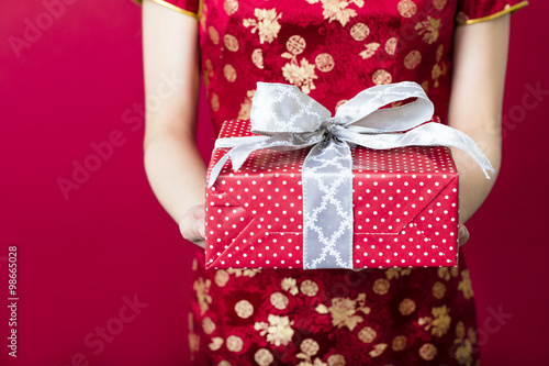 young woman holding gift box on red background