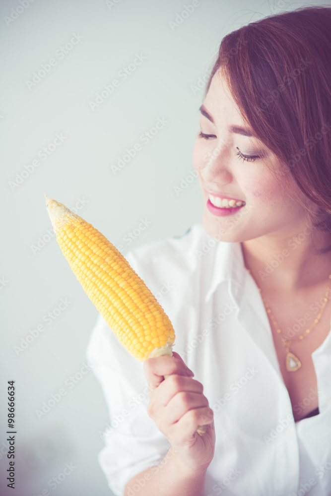 Asian girl eating yellow corn at home. Asian girl eating yellow corn at home.