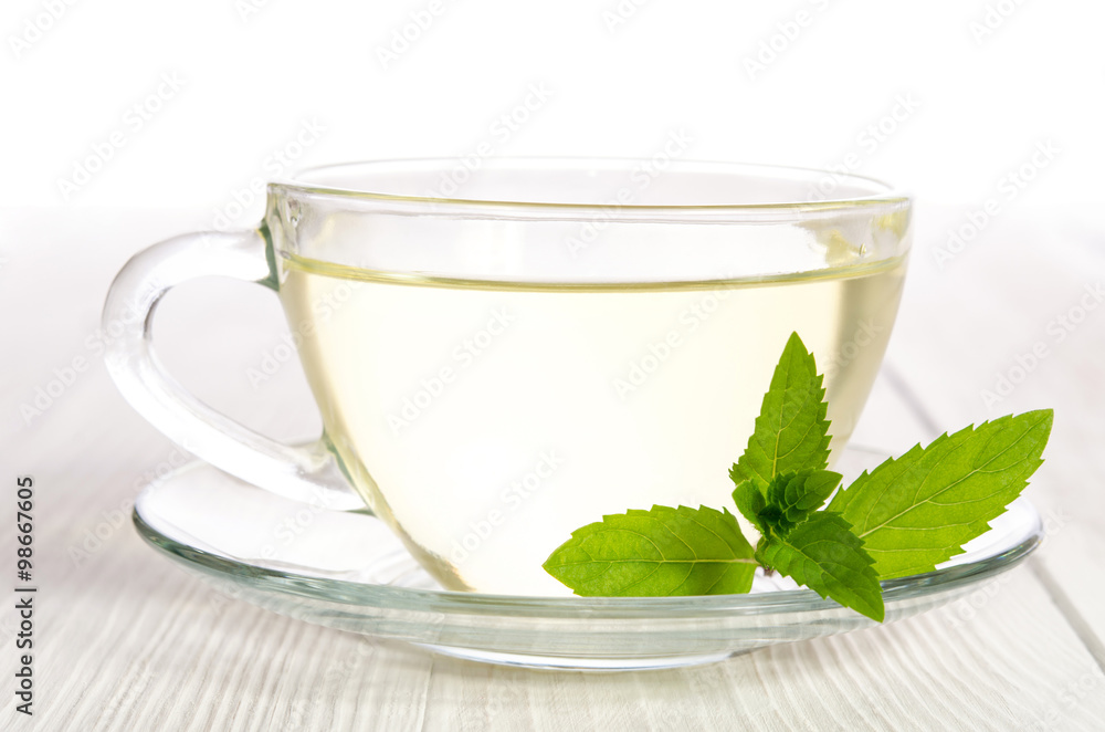 Glass cup of tea with mint on the white wooden table Glass cup of tea with mint on the white wooden table