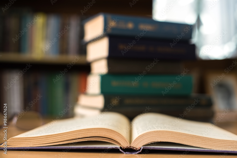 Opened Book and a Stack of Books on the Background Opened Book and a Stack of Books on the Background