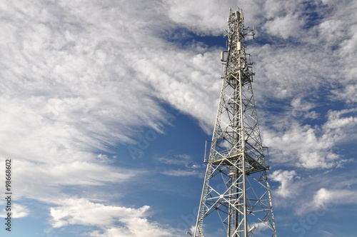 Telecommunication tower against cloudy sky