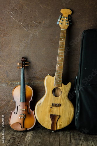 Acoustic guitar and violin resting against an old steel background
