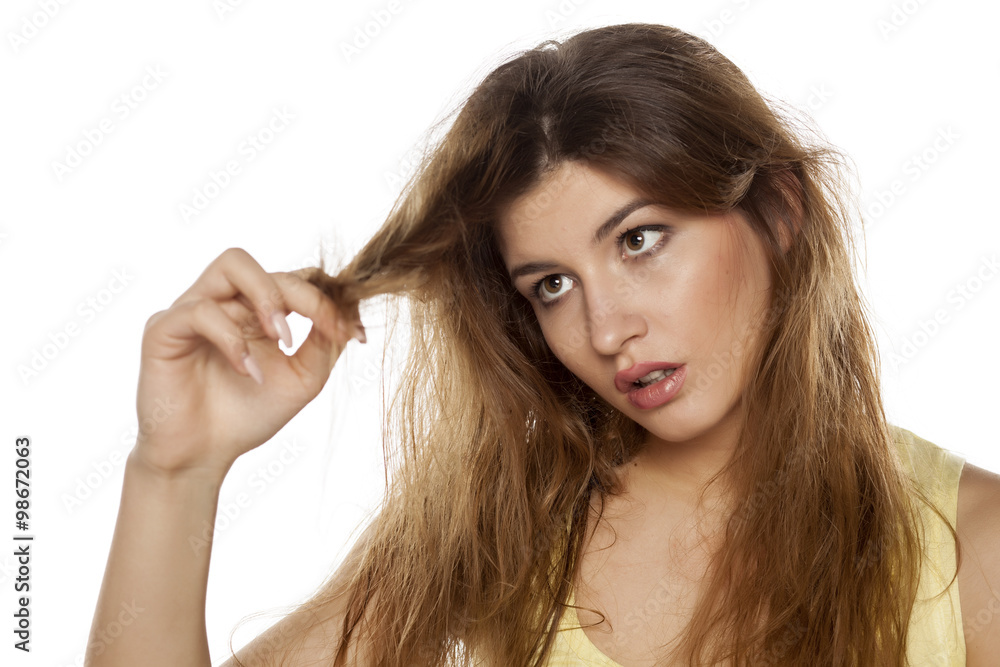nervous young woman looks at the damaged tops of her hair nervous young woman looks at the damaged tops of her hair