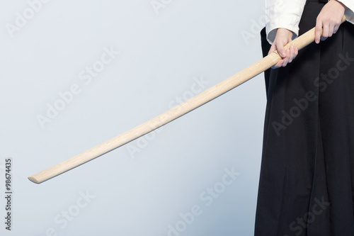 A girl in black hakama standing in fighting pose with wooden katana sword
