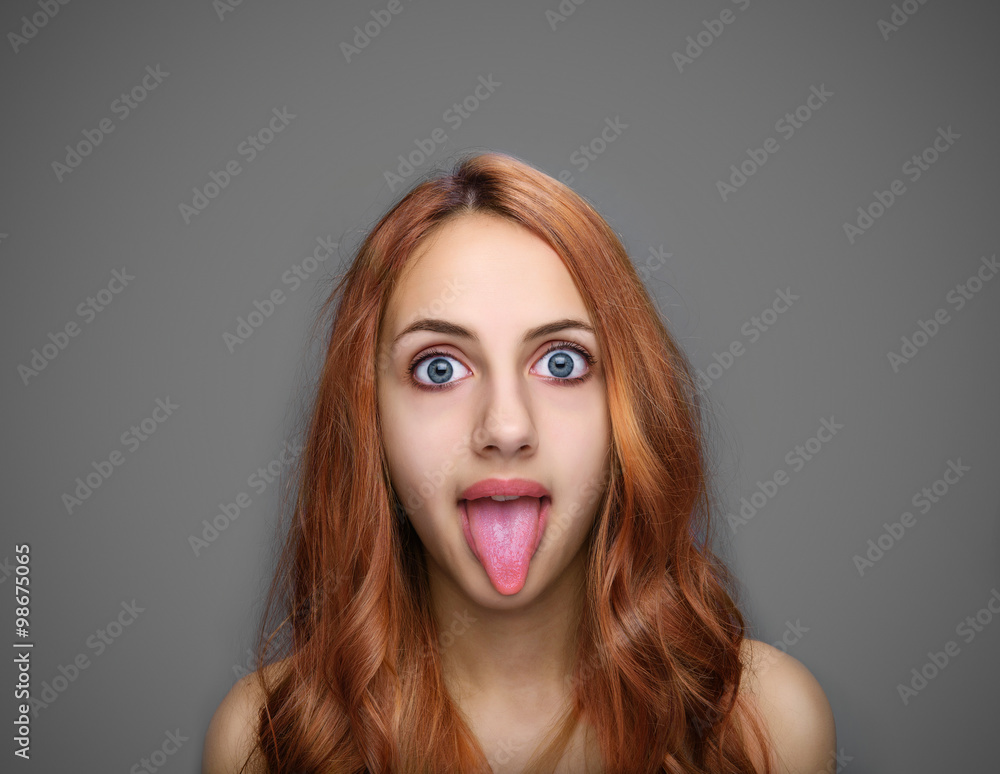 Girl showing tongue isolated on gray. Girl showing tongue isolated on gray.