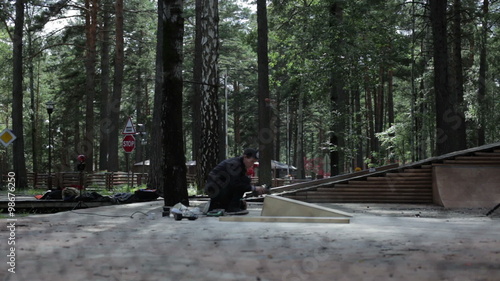 Young man working with a a grinding machine. View through the Rabitz. Summer photo