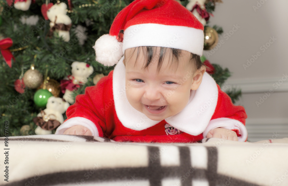 Small child in the clothes of Santa Claus. The girl is lying on her stomach. Small child in the clothes of Santa Claus. The girl is lying on her stomach.