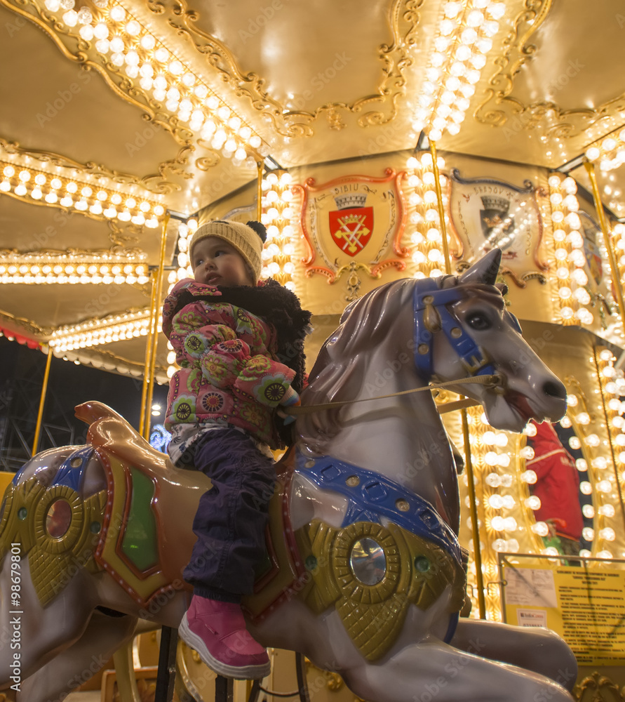 Adorable little girl on a carousel at Christmas market