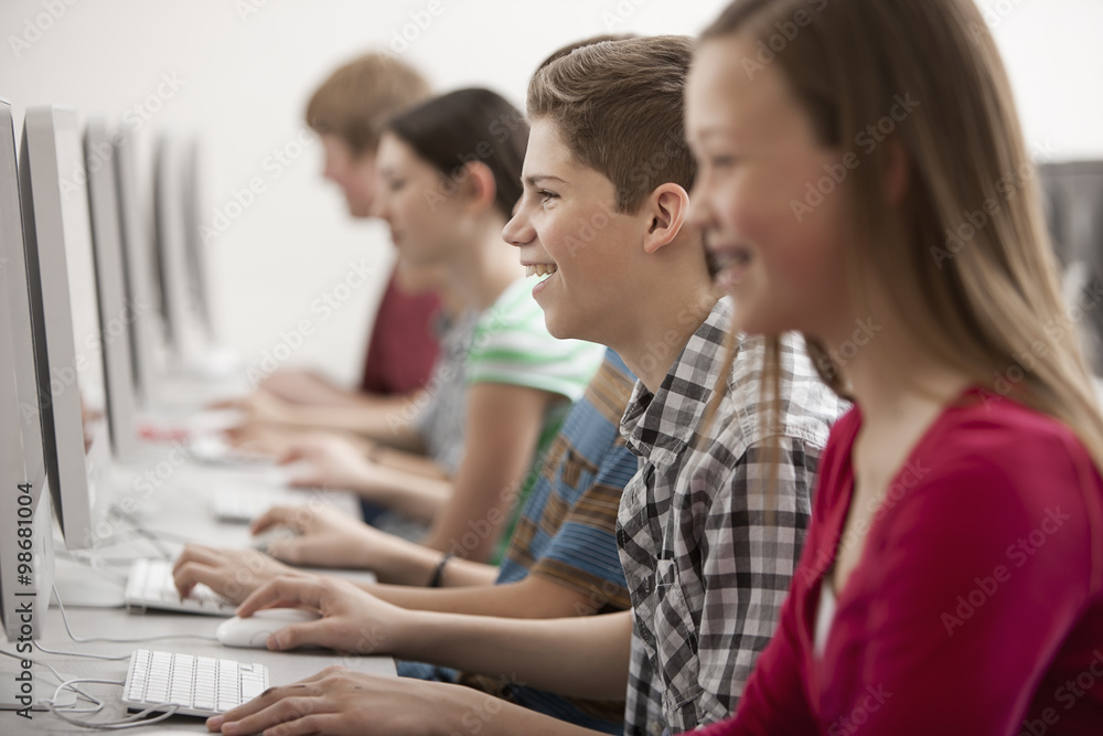 A group of young people, boys and girls, students in a computer class working at screens. A group of young people, boys and girls, students in a computer class working at screens.