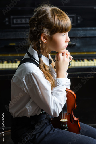 Φωτογραφία pensive girl puts her head on his hands and holding violin