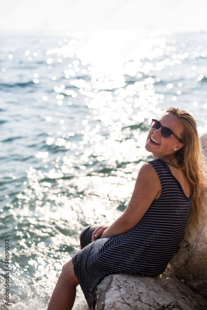 Beautiful woman sitting on a stone and splashing in the sea Beautiful woman sitting on a stone and splashing in the sea