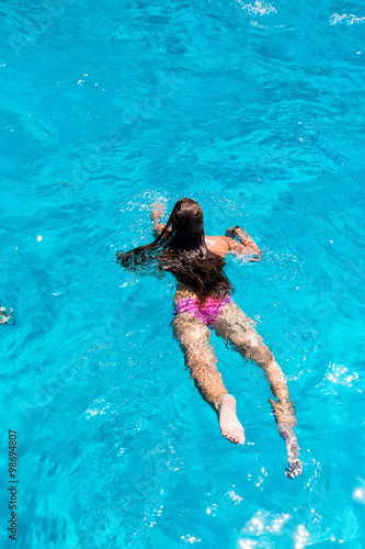 Young woman swimming in clear ocean water.