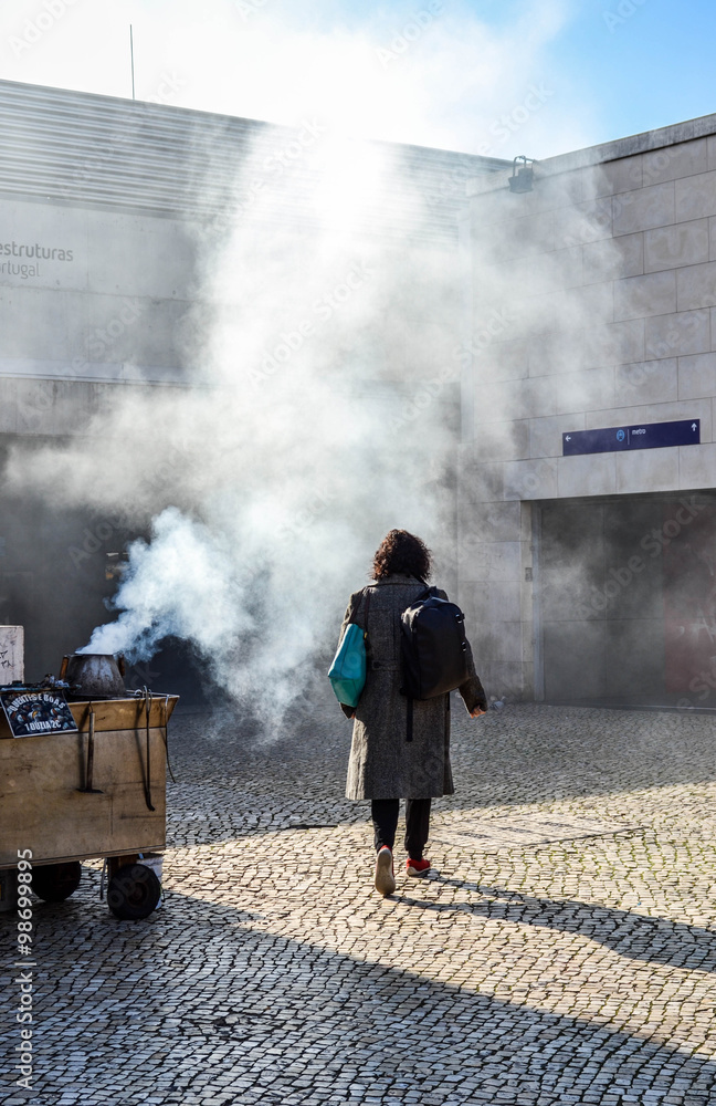 Women walking throug the smoke of roasted chestnuts with a poste