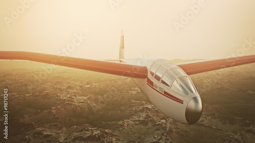 The white sailplane calmly gliding in the sky over the snow-covered mountains.