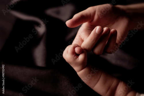 Baby is holding mother's hand