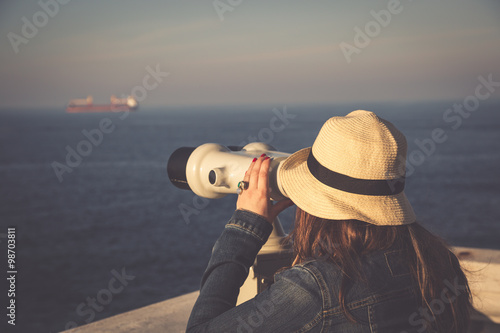 Obraz na płótnie Young girl looking through a coin operated binoculars on the sea w salonie