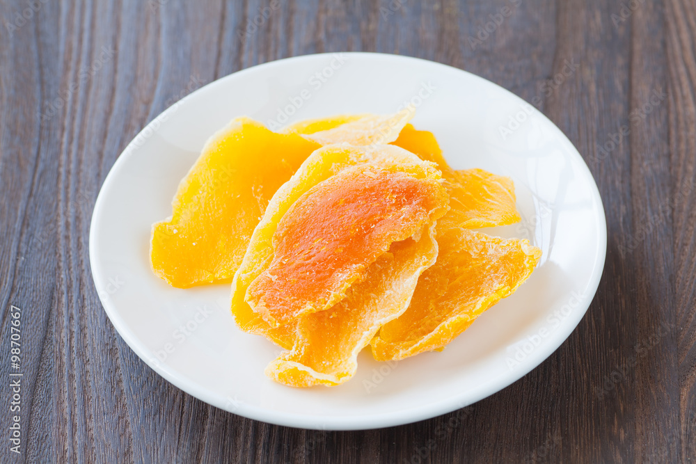 Piece of Dehydrated mango on white ceramic dish Piece of Dehydrated mango on white ceramic dish
