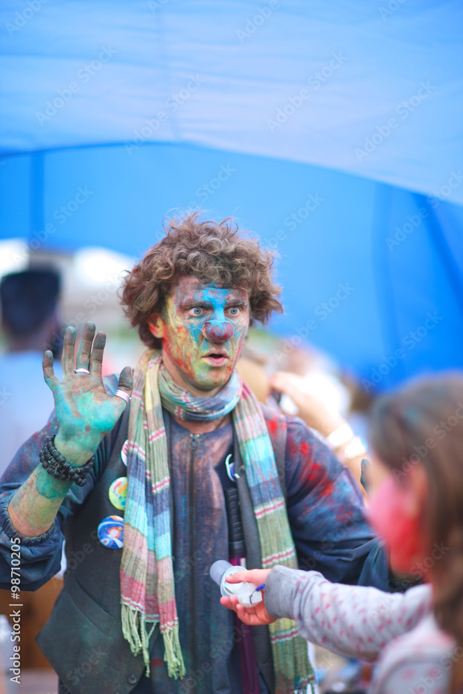Brightly painted clown surrender; professional entertainer at Holi festival