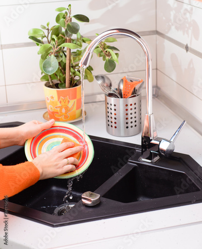 Fotografie Close up hands of woman washing dishes in kitchen