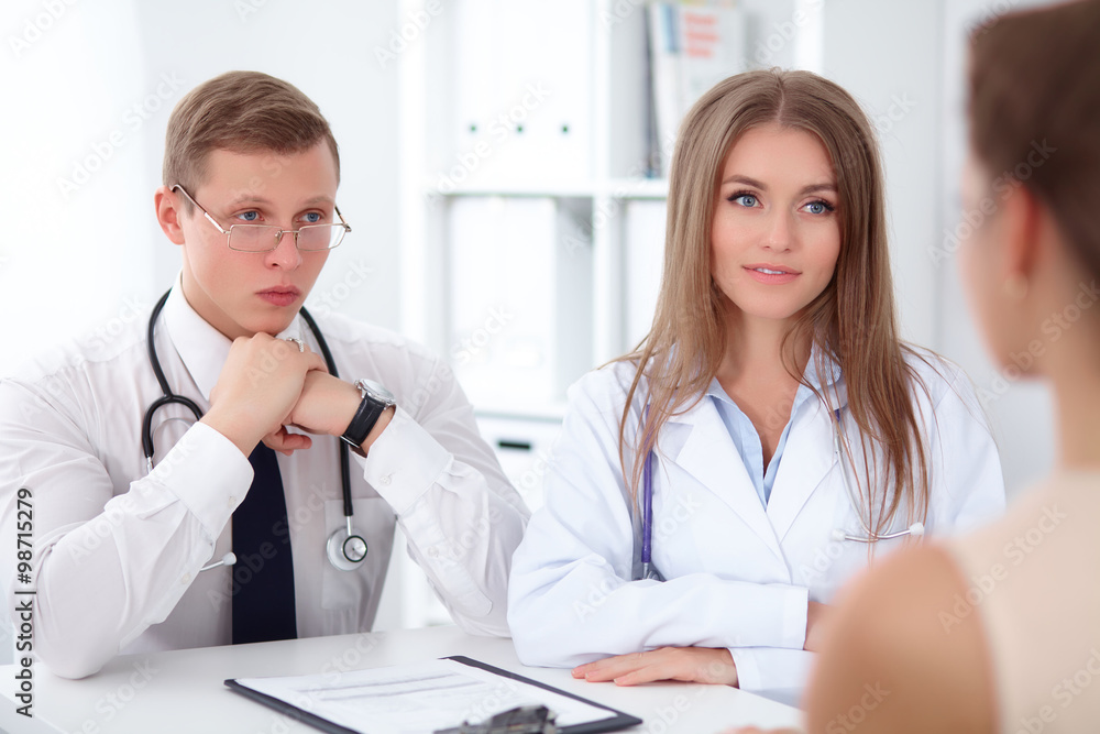 Two confident friendly doctors sitting at the table and listen to the patient's history . Medical and health care concept Two confident friendly doctors sitting at the table and listen to the patient's history . Medical and health care concept