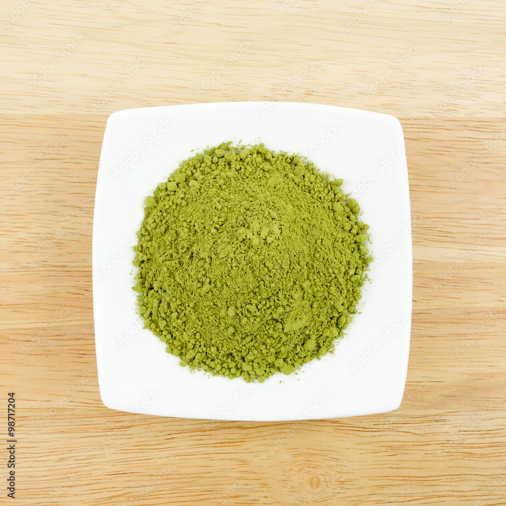 The Japanese matcha green tea powder on the mini white dish on wooden board.