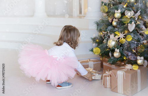 Elegant girl takes a gift under the Christmas tree