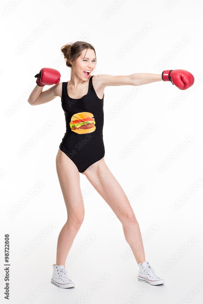 Excited funny young woman in boxing gloves making direct hit Excited funny young woman in boxing gloves making direct hit
