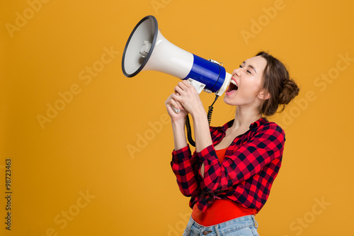 Funny excited young woman shouting in megaphone