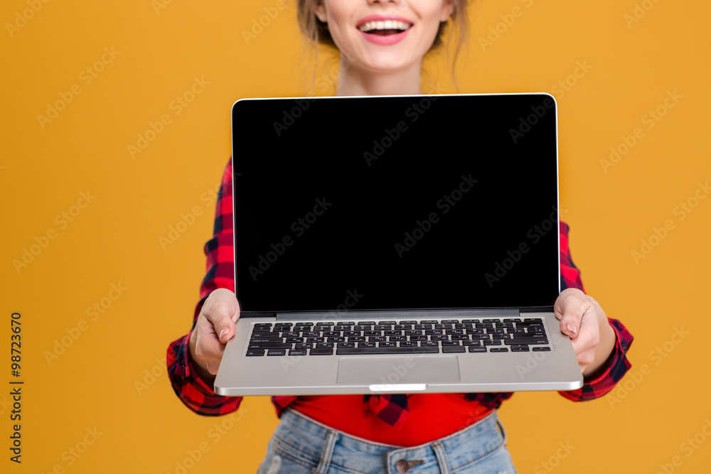Naklejka premium Cheerful cute lovely young woman showing blank screen laptop