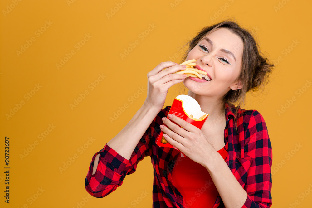 Charming positive young woman in checkered shirt eating fries Charming positive young woman in checkered shirt eating fries